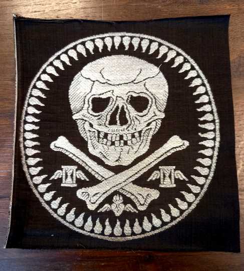 Broderie mortuaire en argent réalisée par les Éts David. Têtes de mort sur fémurs et larmes. Sabliers sur les côtés 