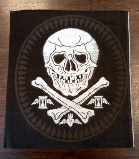 Broderie mortuaire en soie blanche réalisée par les Éts David. Têtes de mort sur fémurs et larmes. Sabliers sur les côtés