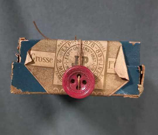 144 (= une grosse de) boutons garance, diam 15 mm, 4 trous à cuvette, dans leur boite d'origine. Fin XIXème.