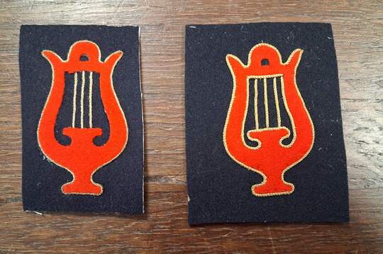 Insigne de spécialité musicien. Lyre découpée rouge, liserée de fil d'or sur drap bleu, cordes dorées . 
