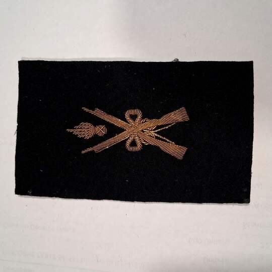 Insigne d'armurier maréchal des logis. Grande guerre. Fusils croisés et grenades entre les canons. Or/noir